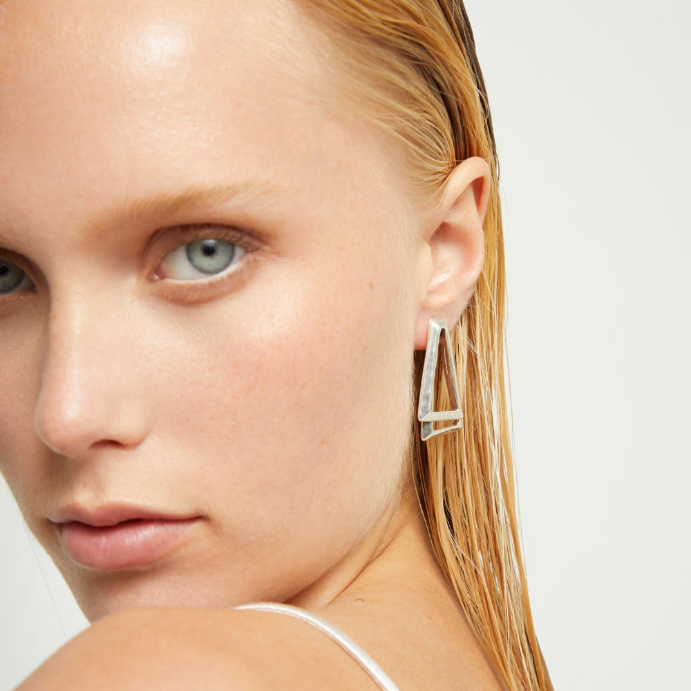 Close-up of a woman wearing a silver earring with a plain background