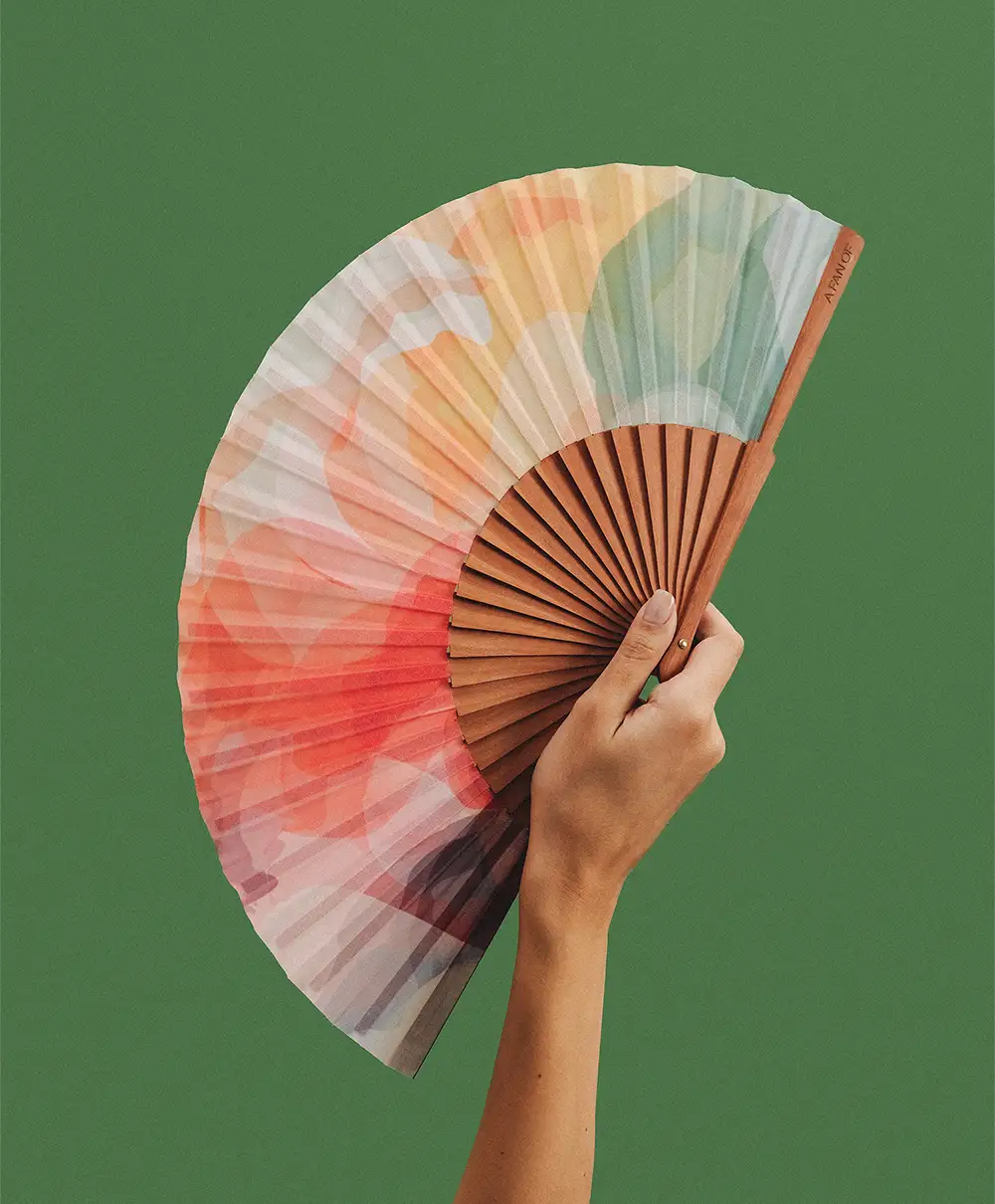 Hand holding a colorful fan against a green background