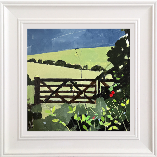 A framed landscape art print depicting a green field with a dark brown wooden gate, lush green foliage, and a deep blue sky, presented in a white square frame.