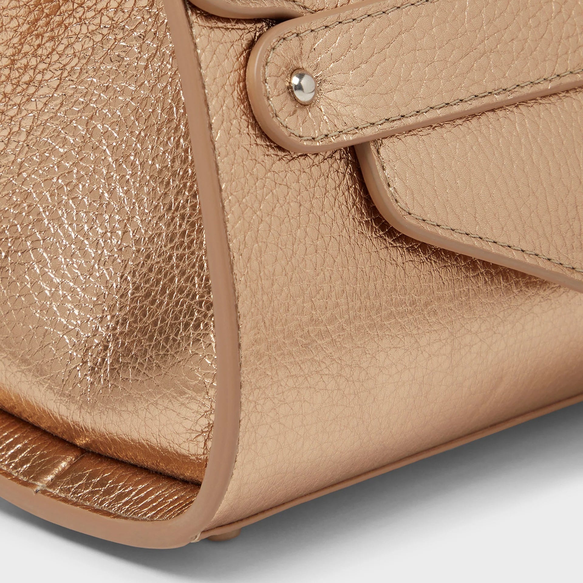 Close-up of a beige leather handbag with a silver clasp on a light gray background