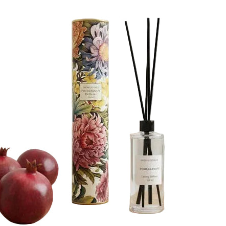 Reed diffuser with floral packaging and pomegranates on a wooden surface