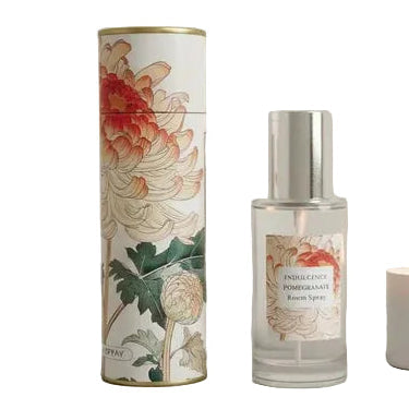 Candle, diffuser, and decorative tube with floral design on a neutral background